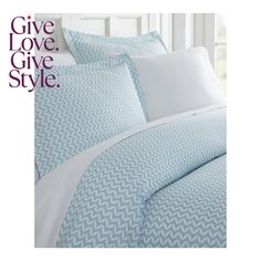 a bed with blue and white sheets, pillows and pillowcases on the cover