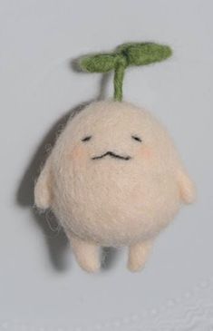 a white stuffed animal with a green leaf on it's head hanging from a hook