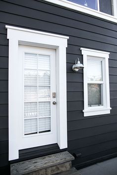 a black and white house with two windows on the front door, and one window in the back