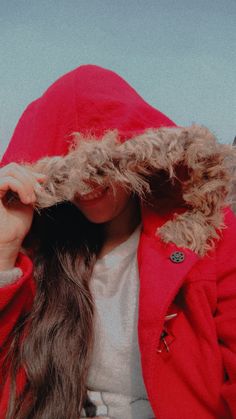 a woman in a red jacket is holding her hair