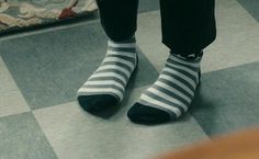 a person wearing striped socks standing on a checkered floor in front of a rug