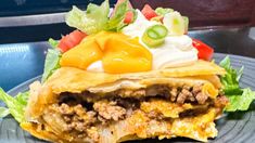 an enchilada with meat, cheese and vegetables is on a blue plate