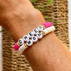 For all my cheer moms! Create your own custom stackable bracelet in your team colors or your personal favorite color combo.  This listing is for two bracelets. Select the color beads and make sure you write the SIZE and either GOLD or BLACK letter beads in the personalization box.  To determine size take a flexible measuring tape or string and measure around your wrist. Then add .5" to get your bracelet size. The most common size is Medium Adult 6.75"  Bracelet is made with elastic (stretchy) cord, 6mm heishi beads, gold plated (brass filled) disks and letter beads.  Please note that all sales are FINAL.  Excited to help you with your bracelet stacks! Be sure to message me with any questions!  Thank you for supporting my small business. White Stacked Stretch Bracelet As Gift, White Stacked Stretch Bracelet Gift, Customizable Fun White Jewelry, Fun Customizable White Jewelry, Pink Stacked Stretch Bracelet As Gift, White Letter Beads Bracelet For Teacher Appreciation, White Stackable Name Bracelet For Friendship, Customizable White Bracelets For Teacher Appreciation, White Stackable Stretch Bracelet For Birthday