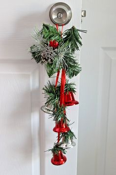 a christmas decoration hanging from a door with bells and pine cones on it's side