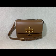 Eleanor Convertible Shoulder Bag/Cross Body Bag By Tory Burch. This Bag Is Made Of Brown Genuine Smooth Leather. This Bag Is Convertible. Can Be Carried As A Shoulder Bag Or Cross Body Bag. Dimensions: 9.25" Wide Across Bottom X 6.25" Tall Center X 2.5" Deep. Adjustable Strap Drop Doubled 11.5", Single 21". Interior: 3 Compartments + 1 Zipper Compartment + 1 Interior Pocket Flap Closure Secured With Magnetic Button. Leather Interior. Gold Tone Metalware. Tory Burch Bag, New Version, Cross Body Bag, Leather Interior, Body Bag, Smooth Leather, Moose, Cross Body, Convertible