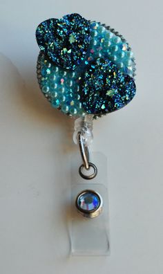 a badge holder with a blue flower on it's side and a beaded charm attached to it