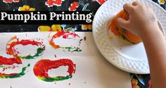 a child's hand is painting the numbers on a paper plate