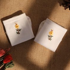 two white napkins with yellow flowers on them