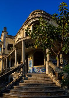 an old building with steps leading up to the front door and stairs down to the second floor