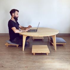 a man sitting at a table with a laptop on his lap and foot stools