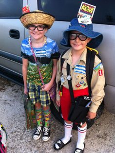 two children wearing hats and glasses standing in front of a van