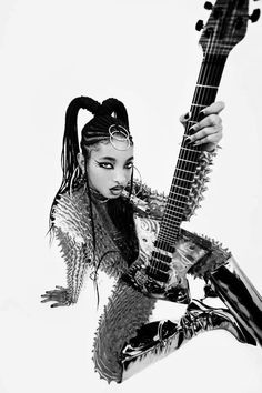 a woman with dreadlocks holding a guitar in her hand and posing for the camera