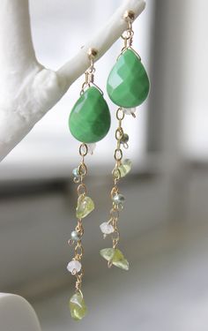 Green-colored quartz earrings with catchers holding a 14k gold-filled chain strung with tumbled peridot (3 per earring), moonstone (2 per earring) and green freshwater pearl (2 per earring).  Also comes with a pair of rubber ear nuts for another simple look. All wire used is 14k gold-filled. Green-colored quartz size: 10mm/0.4in x 13mm/0.5in Freshwater pearl size: 3mm/0.12in Tumbled Peridot size: 5mm/0.2in x 7mm/0.28in Moonstone size: 4mm/0.16in x 2mm/0.08in Length of earring: 6.6cm / 2.6in Hand Green 14k Gold-filled Dangle Earrings, Green 14k Gold Filled Dangle Earrings, Peridot Dangle Earrings For May Birthstone, Yellow Gold Jade Dangle Jewelry, Green Peridot Wire Wrapped Jewelry, Green Wire Wrapped Long Drop Jewelry, Handmade Peridot Dangle Jewelry, Green Peridot Drop Earrings, Green Briolette Wire Wrapped Jewelry