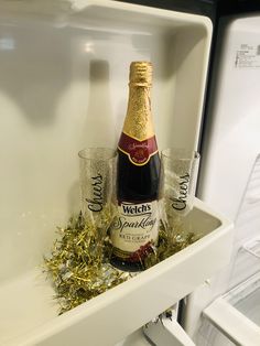 a bottle of champagne and two shot glasses sitting on top of a shelf in a refrigerator