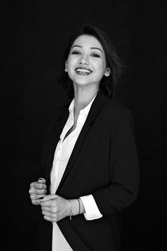 a black and white photo of a woman in a business suit smiling at the camera