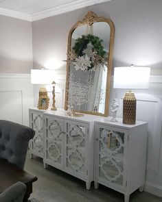 a living room with a couch, chair and large mirror on it's sideboard