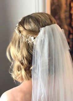 the back of a bride's head wearing a veil and flowers in her hair