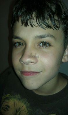 a close up of a young person wearing a black t - shirt and looking at the camera