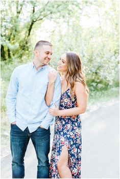 an engaged couple standing next to each other on the road