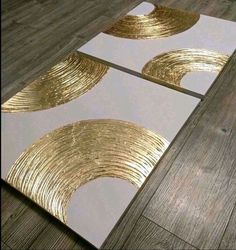 two white and gold coasters sitting on top of a wooden floor