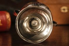 an old metal can sitting on top of a wooden table next to two red apples