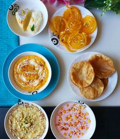 there are many different types of food on the plates and in bowls, along with bread