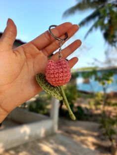 a hand holding a tiny crocheted flower keychain