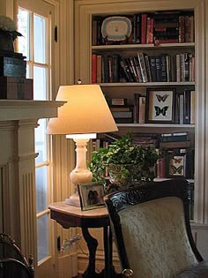 a living room filled with furniture and a lamp next to a book shelf full of books