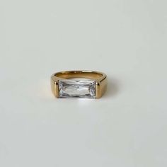 a gold ring with a baguette cut diamond in the center on a white background