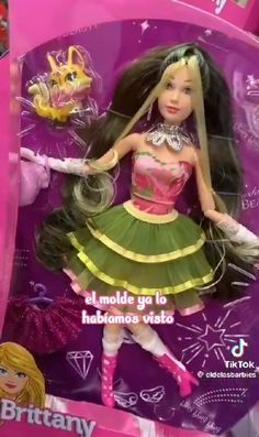 a barbie doll with long black hair and green dress in a pink box on display