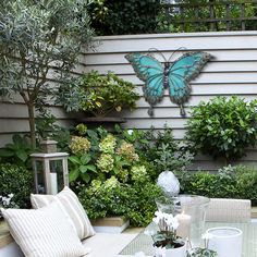 a table with some flowers and plants on it in front of a butterfly wall decoration