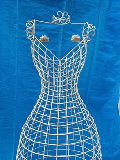 a mannequin made out of wire is shown against a blue backdrop with gold accents