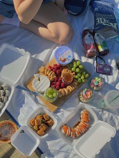 a person laying on a blanket with food and drinks in containers next to it,