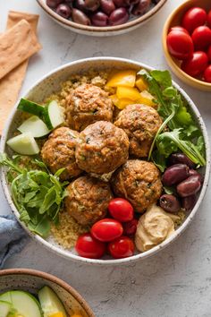 two bowls filled with meatballs and vegetables next to some pita bread on the side