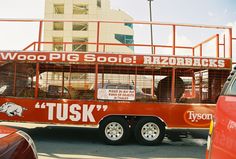 a red tour bus parked in front of a tall building with an advertisement on the side