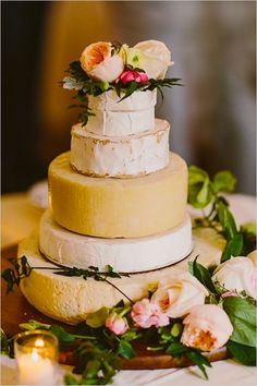 a wedding cake sitting on top of a wooden platter with flowers and greenery