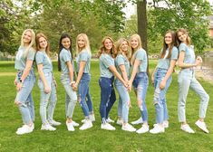 a group of young women standing next to each other on top of a lush green field