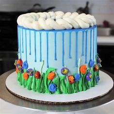 a blue cake with white icing and flowers on it