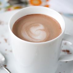 a cup of hot chocolate on a saucer with a spoon and fork next to it