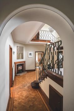 an arched doorway leading to a living room and dining area with wood flooring on either side