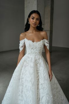 a woman in a white wedding dress with an off the shoulder top and long skirt