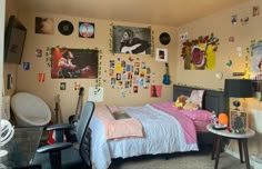 a bed room with a neatly made bed and lots of pictures on the wall above it