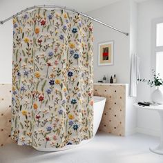 a white bath tub sitting next to a shower curtain in a bathroom with flowers on it