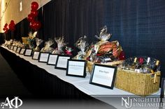 a long table topped with lots of items and framed pictures next to red balloons in the background