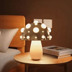 a lamp that is on top of a table next to a book and some pillows