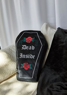 a dead inside sign sitting on top of a black pillow next to a white curtain