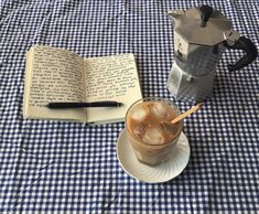 an open book sitting on top of a table next to a cup of iced coffee