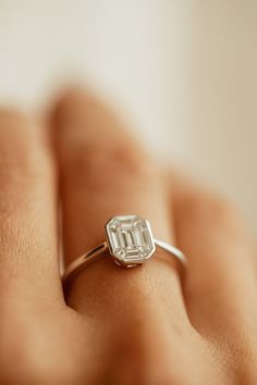 a woman's hand with a diamond ring on top of her finger, showing the center stone