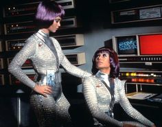 two women in silver outfits standing next to each other