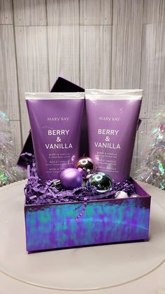 two bottles of berry vanilla on top of a purple box with ornaments in the background